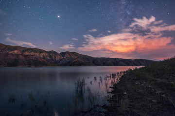 Fototapeta premium Mountains and lake in the starry night. Beautiful night landscape..