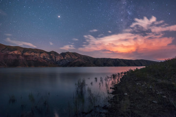Mountains and lake in the starry night. Beautiful night landscape..