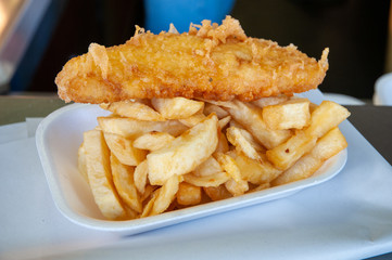 Unhealthy fast food portion of deep fried fish and chips from traditional takeaway chip shop, UK