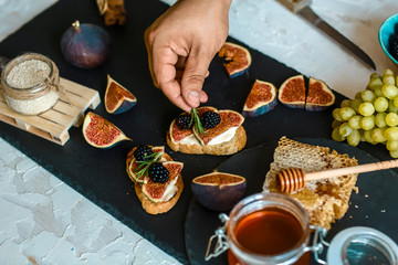 Chef hands cooking snacks with cheese, honey and figs on a shale board. Food concept