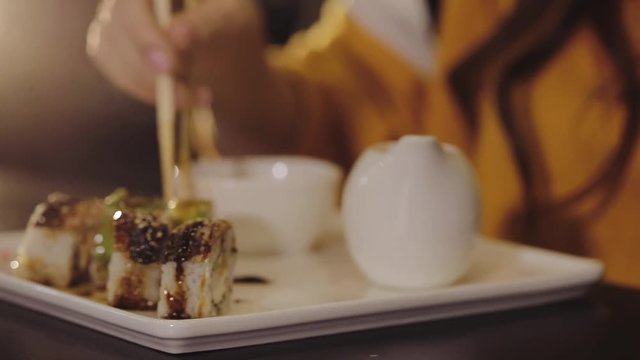 Girl eating sushi set with chopsticks on Japan restaurant, close up