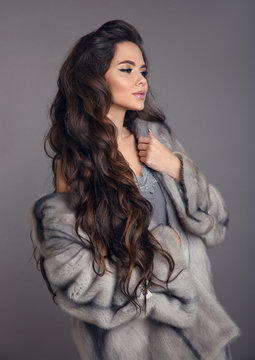 Elegant woman in mink fur coat isolated on gray studio background. Fashion Brunette Girl in Luxury Winter outerwear.