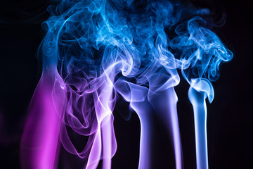Colorful smoke of incence stick isolated at black background