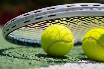 Tennis balls and racket on green tennis hard court