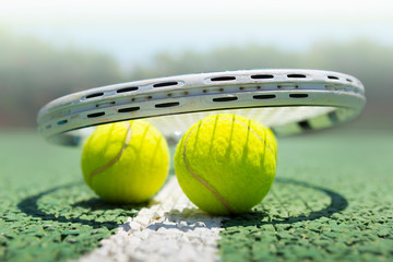 Tennis balls and racket on green tennis hard court