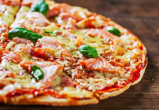 Pizza with Mozzarella cheese, salmon fish, tomato sauce. Italian pizza on wooden table background