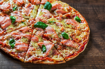 Pizza with Mozzarella cheese, salmon fish, tomato sauce. Italian pizza on wooden table background