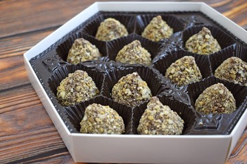 Delicious chocolates in a box on wooden background.