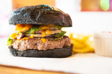 Big Black Tasty Sandwich - Hamburger Or American Burger With Beef, Pickles, Tomato And Sauce On Table. Concept Fast And Unhealthy Food, Unhealthy Eating.