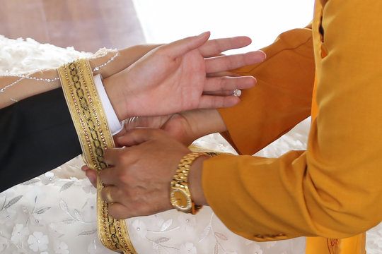 Monks or priest handfasting yellow ribbon at groom and brides hand. Buddhist theravada wedding ceremony.