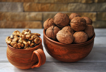 Walnut peeled and inshell in pottery on a white wooden table.