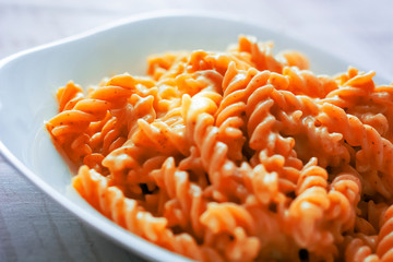 closeup of a plate of fusilli pasta with red tomato sauce.