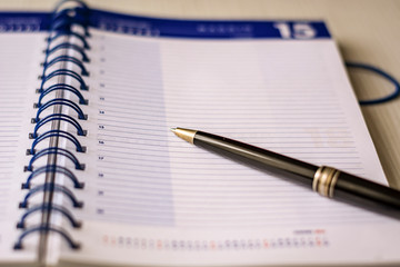 a black pen on an open spiral notebook. Business and scheduling concept