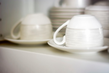 Fototapeta na wymiar decorated coffee mugs kept in a shelf of a white pantry