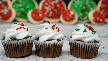 Close up view of chocolate Christmas holiday cupcakes with sprinkles and vanilla buttercream frosting. Copyspace in background
