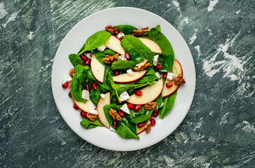 Spinach Salad, Apple, Pomegranate, Cheese, Walnut Salad on Concrete, Slate Background