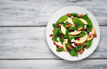 spinach salad, apple, pomegranate, cheese, walnut salad on wooden steel