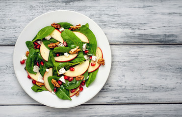 spinach salad, apple, pomegranate, cheese, walnut salad on wooden steel