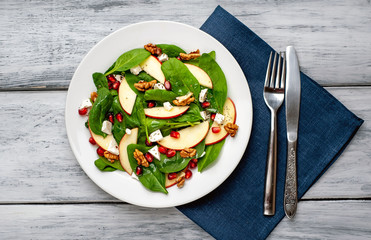 spinach salad, apple, pomegranate, cheese, walnut salad on wooden steel