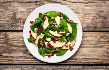 spinach salad, apple, pomegranate, cheese, walnut salad on wooden steel