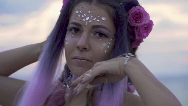Tender young woman with sparkling makeup pierced nose in a pink dress dancing outdoors. The dance of a sweet sensual lady with a flower hairstyle. Slow motion.