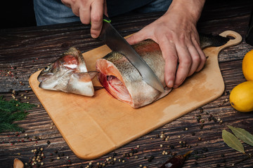 man cuts knife red fish on wooden Board