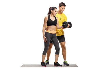 Young female exercising with a dumbbell with the help of a male instructor