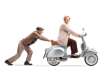 Elderly man pushing an elderly woman on a vintage motorbike