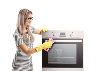 Young woman with gloves cleaning an oven