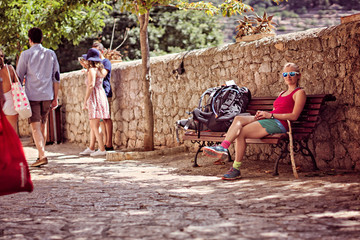 Backpacker girl resting on a busy street in Mallorca, Spain