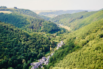 Fototapeta na wymiar Top view of the small village surrounded by green hills covered with forest