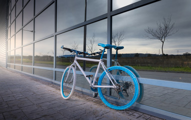 white and blue bicycle on metal wall supported