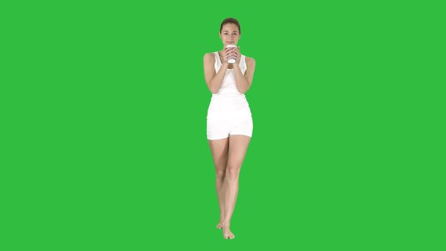 Woman walking and drinking coffee on a Green Screen, Chroma Key.
