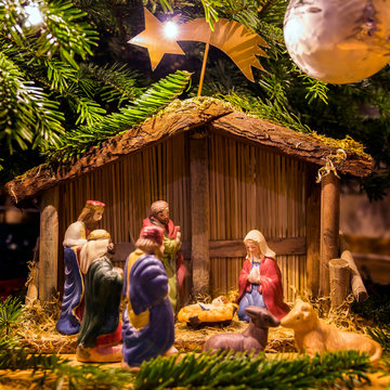 Krippe mit Jesus, Josef, Maria, den heiligen drei K&ouml;nigen und einer Kuh und einem Esel unter einem beleuchteten Weihnachtsbaum. 