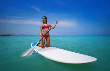 Girl rowing on knees on paddle surf SUP