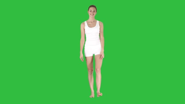 Young sexy woman walking and smiling dressed in white shorts and t-shirt on a Green Screen, Chroma Key.