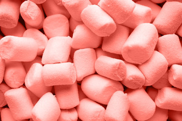 A pile of small living coral color puffy marshmallows.