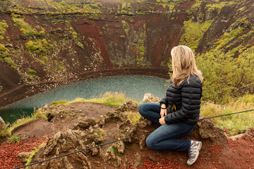 Mujer joven mirando un volcán en Islandia.