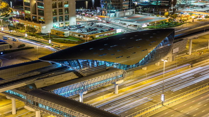 Fototapeta na wymiar Metro station near Buildings of Jumeirah Lakes Towers with traffic on the road night timelapse.