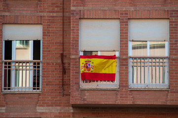 Flag of Spain hanging on the balcony of a house as a symbol of support for Spanish nationalism in...