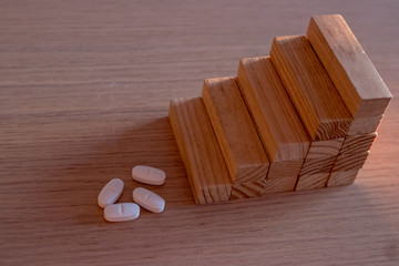 Pharmaceutical and medical expenditure concept with pills and wooden pieces