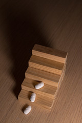 Pharmaceutical and medical expenditure concept with pills and wooden pieces