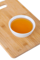 Fototapeta na wymiar honey in a white ceramic bowl on a wooden kitchen board, white background