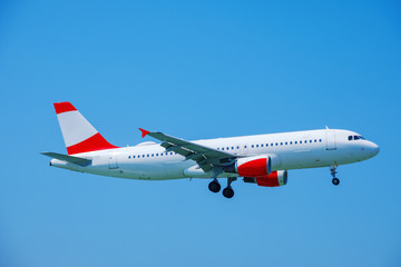 A passenger plane flying in the blue sky, preparing for landing