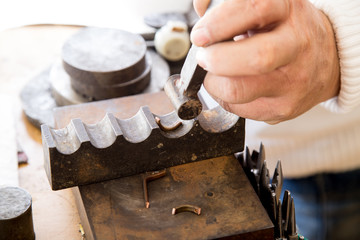 Złotnik w pracowni jubilerskiej wykonuje biżuterię.