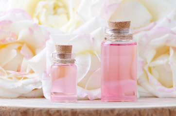 Fototapeta na wymiar glass bottles of aroma oil and fresh rose flowers, selective focus