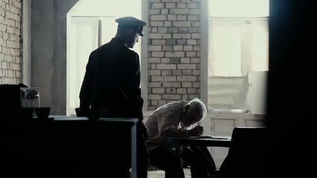 Soldier of the Russian army interrogates a suspect, an elderly man with a beard, under pain of execution, signs papers, the injustice of the NKVD, cynicism of the soldiers, the cruelty of the USSR