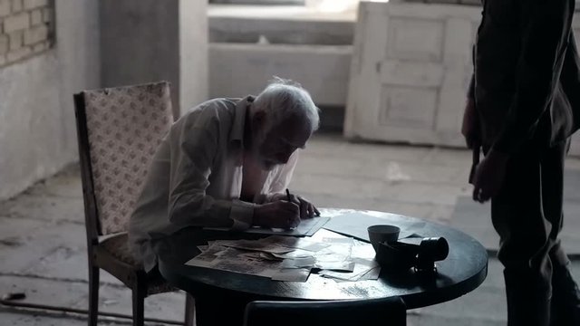Soldier of the Russian army interrogates a suspect, an elderly man with a beard, under pain of execution, signs papers, the injustice of the NKVD, cynicism of the soldiers, the cruelty of the USSR