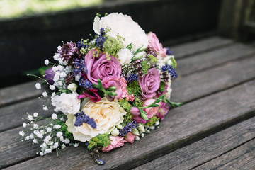 Bridal bouquet placed on an old wooden table by the bride