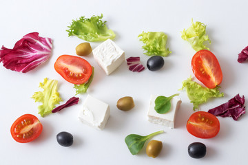 Greek salad, white Greek cheese, green and black olives, lettuce leaves, halfs of cherry tomato. White background. variations of salad leaves and feta myzithra cheese.